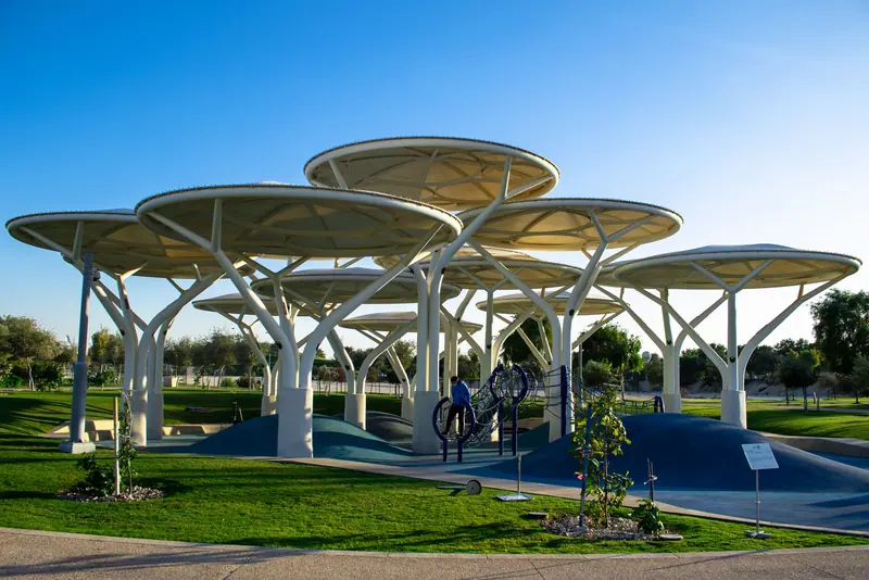 Sculptural shade structures and playground equipment in a modern park